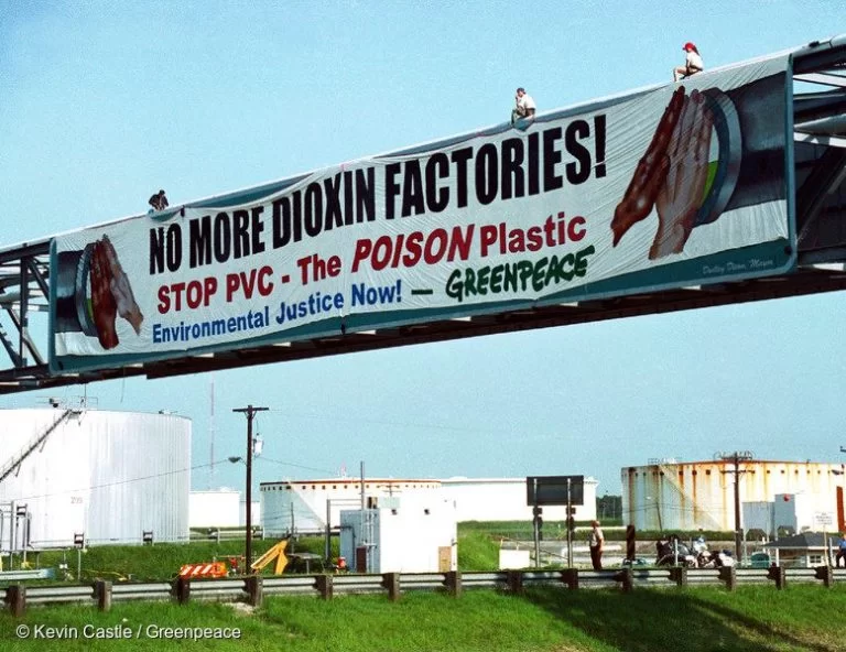 Activists display a banner from pipes carrying PVC chemicals.
The banner reads: ‘No More Dioxin Factories! Stop PVC – The Poison Plastic’.